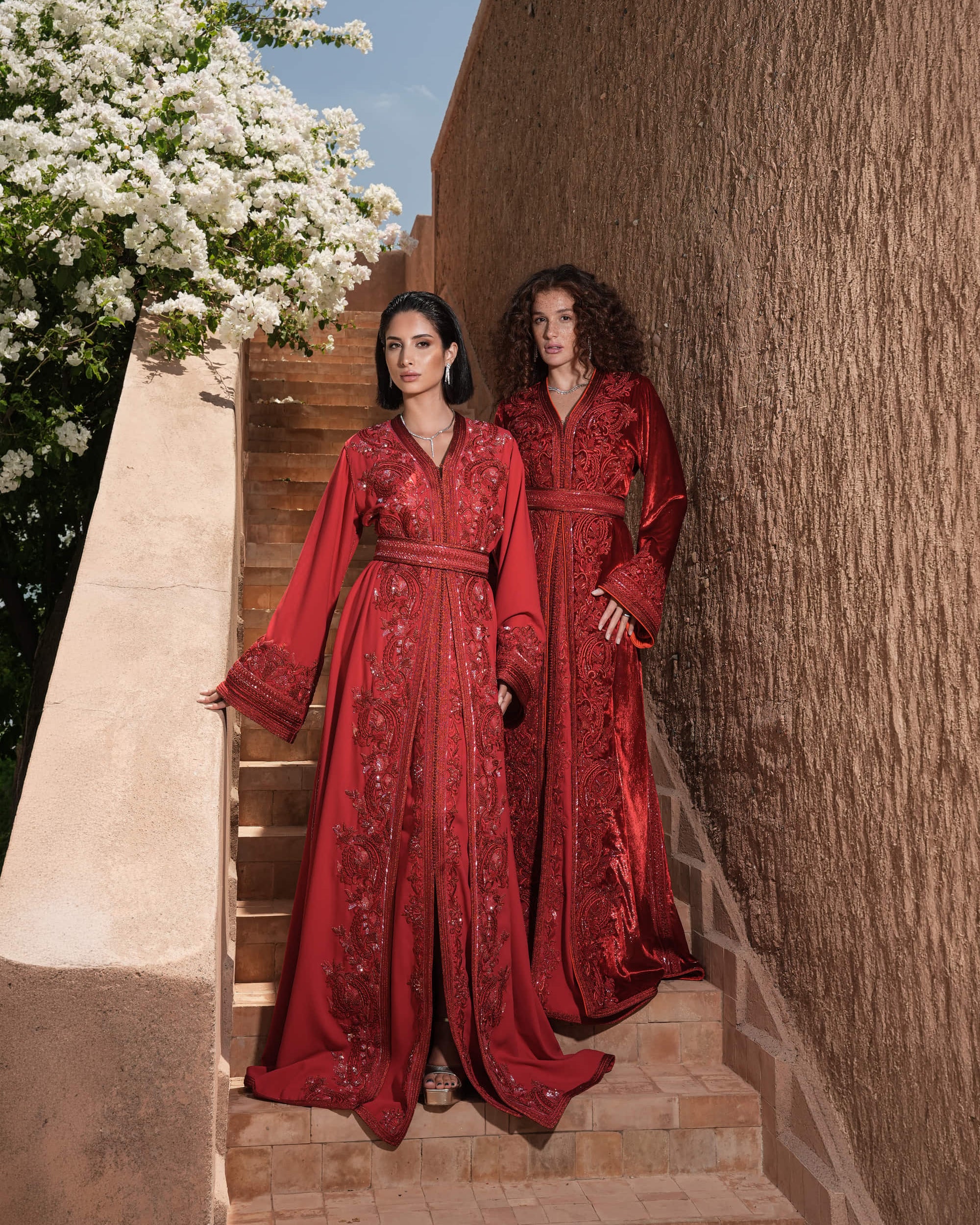 Garnet Adagio burgundy velvet Moroccan kaftan with tone-on-tone embroidery, matching belt and wide sleeves, shown alongside a second look
