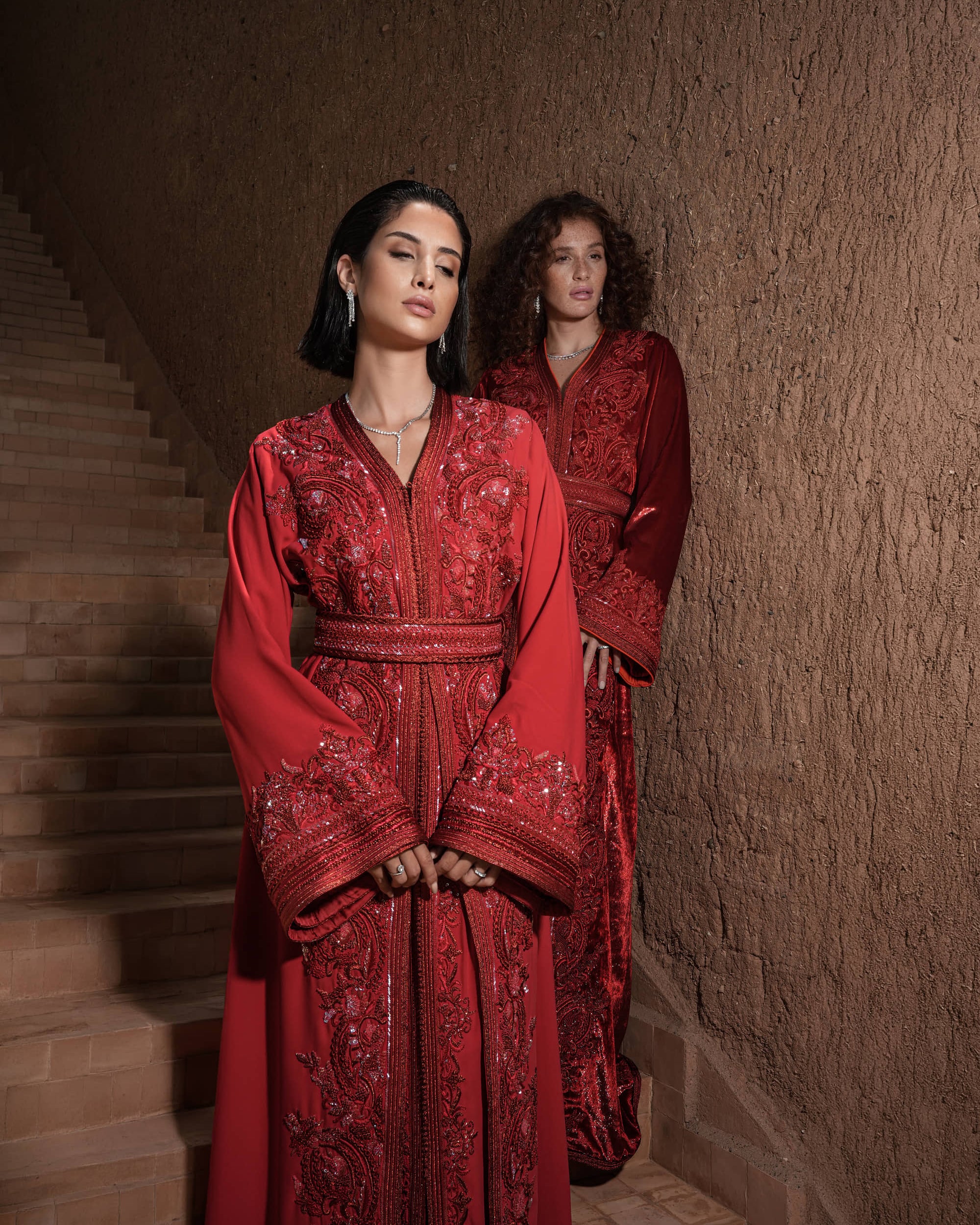 Garnet Adagio burgundy velvet Moroccan kaftan with tone-on-tone embroidery, matching belt and wide sleeves, shown alongside a second look