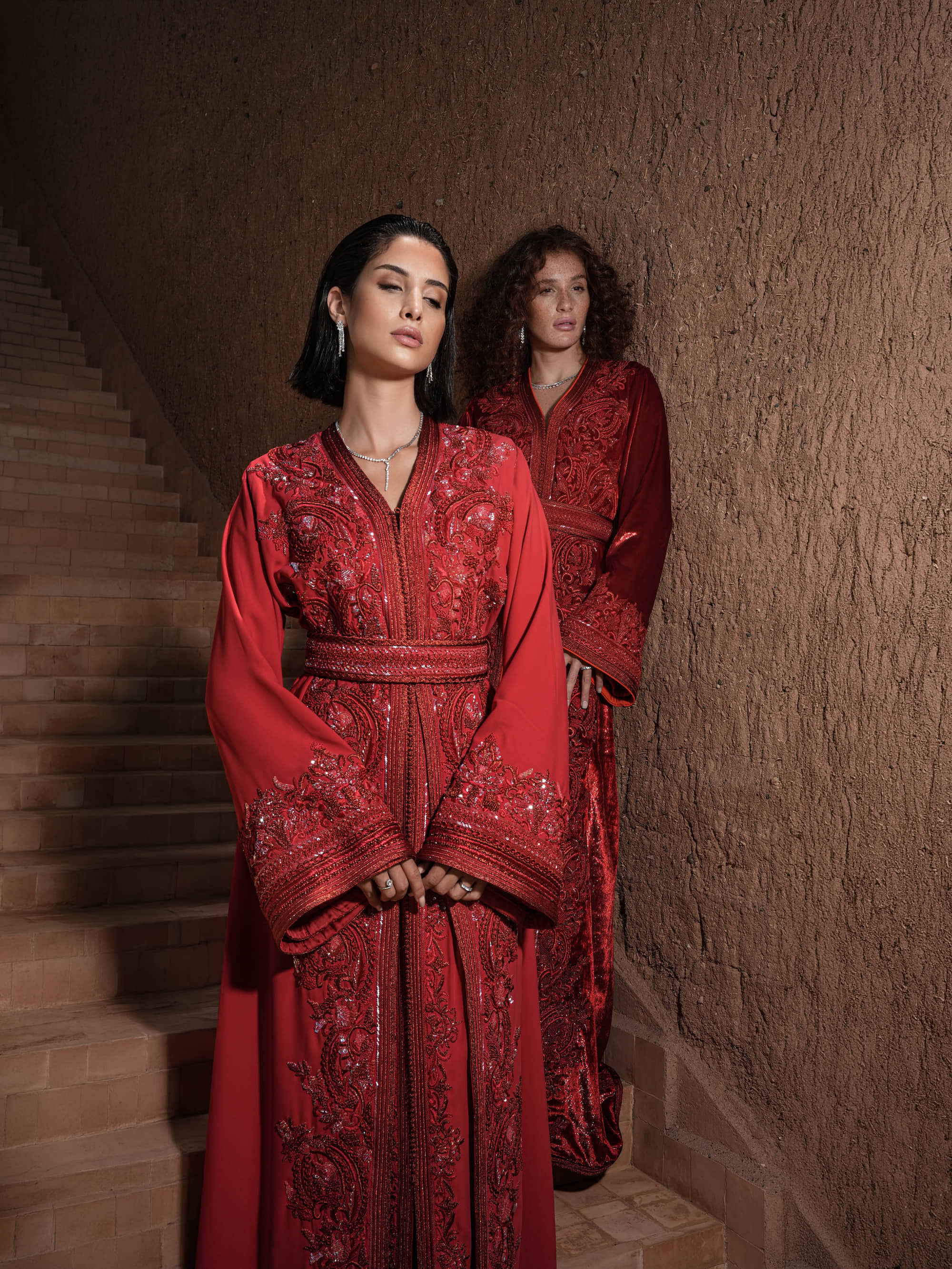 Garnet Adagio burgundy velvet Moroccan kaftan with tone-on-tone embroidery, matching belt and wide sleeves, shown alongside a second look