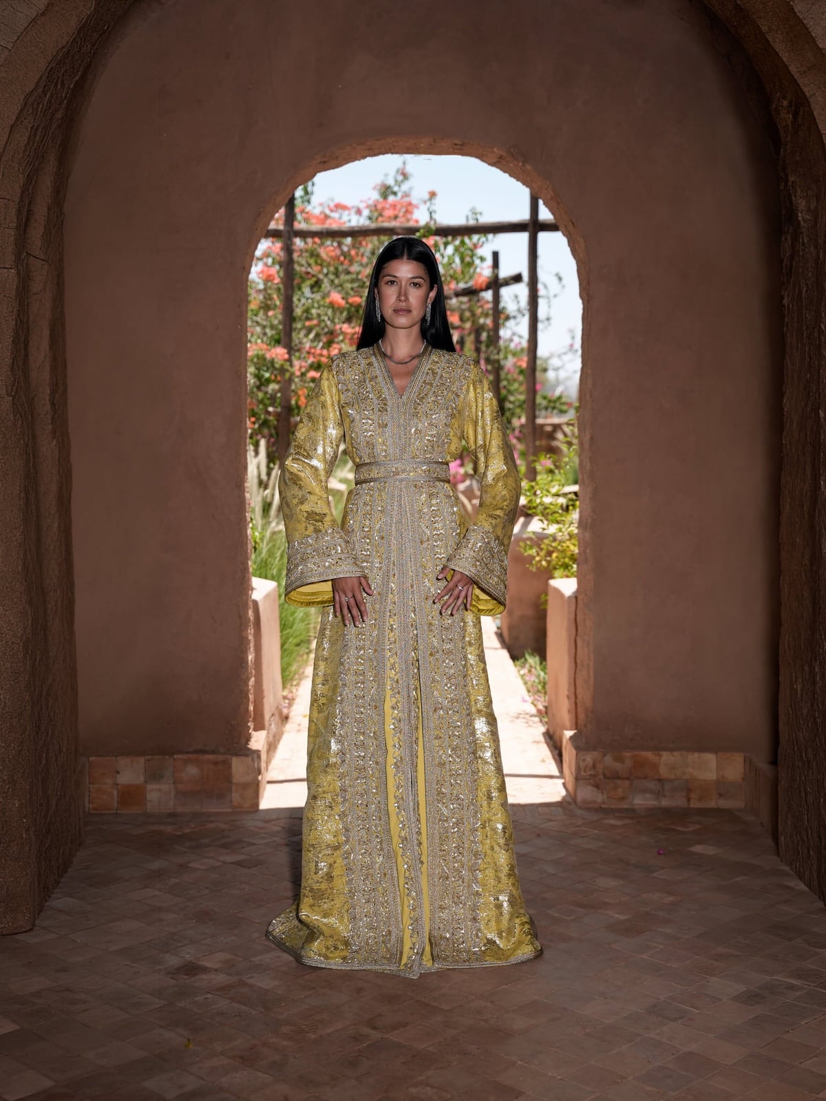 Citron Prelude embroidered Moroccan kaftan framed by an adobe archway